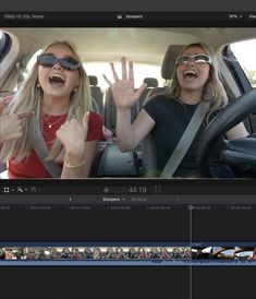 two women sitting in the back seat of a car with their hands up and smiling