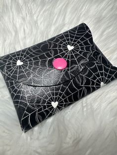 a black and white spider web purse with a pink button