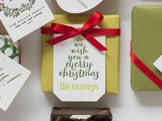 christmas presents are wrapped in green and white paper with red ribbon around them, along with tags that say we wish you a merry christmas