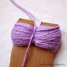 a purple ball of yarn on top of a piece of brown paper with twine