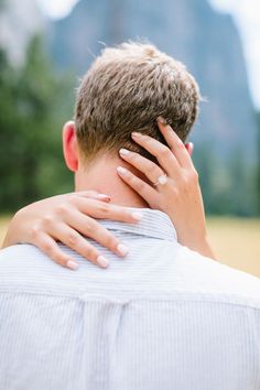 a man and woman embracing each other in front of mountains