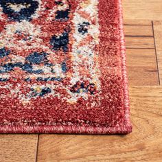 a red area rug with blue and white designs on the top is laying on a wooden floor