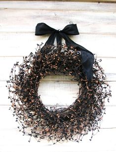 a black wreath with a bow hanging on a wall