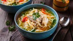 two bowls of chicken noodle soup on a wooden table