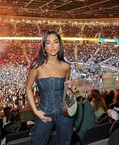 a woman standing in front of a crowd at a basketball game with her hand on her hip