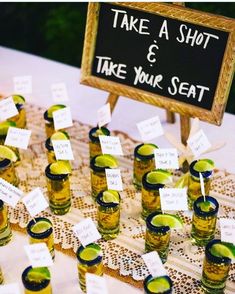 there are many glasses with limes in them on the table next to a sign that says take a shot and take your seat