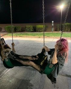 a woman with pink hair sitting on a swing