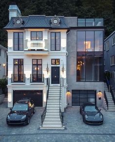 two cars are parked in front of a large house with stairs leading up to the second floor