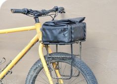 a yellow bicycle with a black bag on it's front rack and handlebars