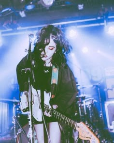 a woman with long hair playing guitar on stage