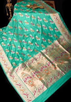 This teal Banarasi Katan silk saree with Meenakari Peacock design Motifs and Paithani style tissue and meena Borders and pallu add elegance and style to the overall look. Perfect for special occasions, this saree tells tall tales of craftsmanship! SILK MARK CERTIFIED This saree is ready to wear with fall and pico done. Handmade silk tassels adorn the pallu and add more grace to it. An unstitched blouse fabric is included. *Note: There may be minor variations in the shade, the texture of the product. Hues/textures show differently due to variations in screen settings and other factors, *Note: This is a handwoven saree and there may be slight inconsistencies such as in it's weaving. These are characteristic of handmade products and attest to their originality and are not considered as defect Luxury Saree With Peacock Design, Luxury Peacock Design Saree For Puja, Luxury Art Silk Saree With Peacock Design, Luxury Saree With Peacock Design For Puja, Luxury Katan Silk Dupatta With Peacock Design, Banarasi Katan Silk Saree, Peacock Motifs, Design Motifs, Silk Tassels