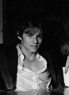 black and white photograph of a young man sitting in front of a table with water on it