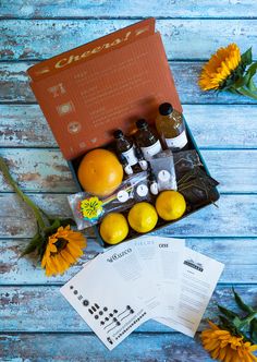 an open box containing oranges, lemons and other items on a blue wooden table