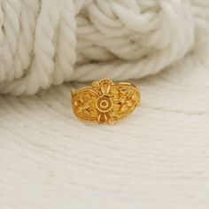 a gold ring sitting on top of a pile of white yarn