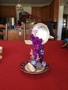 a plate with flowers on it sitting on top of a red tablecloth covered table