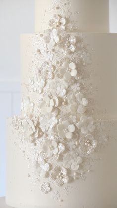 a wedding cake with white frosting and flowers on the top tier is decorated with pearls