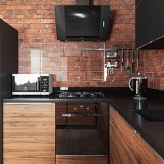 a kitchen with brick walls and black counter tops, microwave, toaster oven and coffee maker