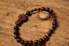 +.This is a rosary bracelet made of wood. The crucifix and the beads are constructed of wood. +.The wooden rosary is beneficial because you can feel the softness of the wood while praying. The more you contact wood, the more it takes on a natural brilliance. +.Surinamese ebony was used to make the crucifix. The light brown tone of Surinamese ebony is appealing. Surinamese ebony is so hard that it may be carved finely. It is carved over a long period of time rather than molded for a few minutes. Handmade Brown Rosary Bracelet As Gift, Spiritual Brown Rosary Bracelet For Gift, Handmade Cross Rosary Bracelet For Blessing, Handmade Cross-shaped Rosary Bracelet For Blessing, Gift Rosary Bracelet With 8mm Beads And Crucifix, Spiritual Rosary Bracelet With Cross Shape, Spiritual Rosary Bracelet With Cross For First Communion, Spiritual Cross Rosary Bracelet For Gift, Spiritual Cross Rosary Bracelet Gift