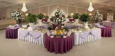 a banquet hall with tables covered in purple and white tablecloths, decorated with flowers