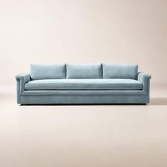 a light blue couch sitting on top of a white floor next to a beige wall