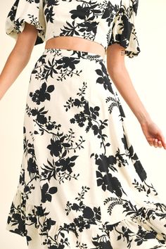 a woman in a black and white floral print dress with her hands on her hips