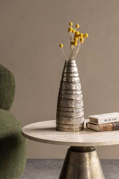 a vase with yellow flowers sitting on top of a table next to a green chair