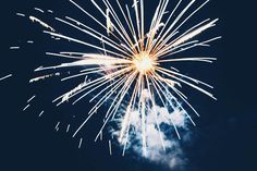 fireworks in the night sky with clouds and blue sky behind it, as seen from ground level