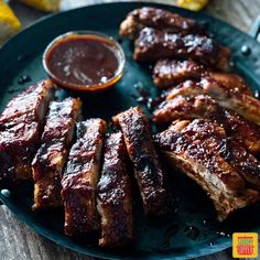 barbecue ribs and sauce on a plate with lemon wedges in the backgroung