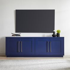 a large television mounted on top of a blue cabinet in front of a white wall