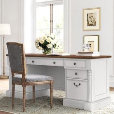 a white desk with two chairs and a vase of flowers sitting on top of it