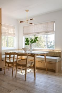 a dining room table with chairs and a bench in front of the window that overlooks trees