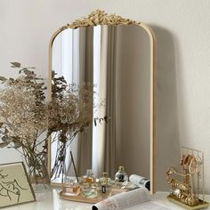 a mirror sitting on top of a table next to a vase