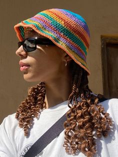 a woman wearing sunglasses and a multicolored hat with braids on her hair