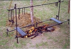 a fire pit in the middle of a field next to a tree and swing set