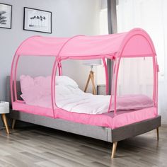 a pink canopy bed with white sheets and pillows