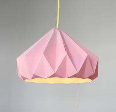 a pink origami light hanging from a yellow cord