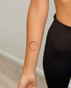 a woman's arm with a small circle tattoo on the left side of her right arm