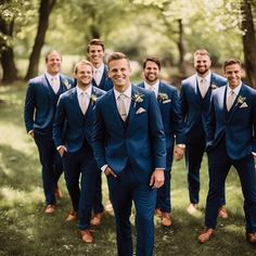 a group of men standing next to each other wearing blue suits and bow ties in the grass