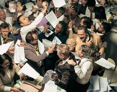 a large group of people standing around each other in the middle of a pile of papers