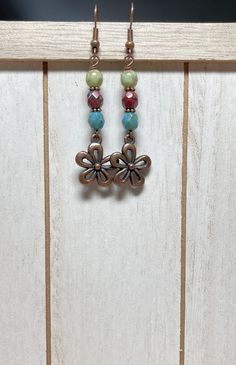 "Boho style earrings with rustic vibes!  These were created using Czech Picasso glass beads in sage, sky blue, and dark maroon red.  I have also used copper spacer beads, and antique copper flower charms.  Great casual, everyday earrings! Total length of earrings, including the ear wire, is slightly over 2-1/4\".   Matching necklace: https://www.etsy.com/listing/1601876489/rustic-beaded-czech-glass-necklace-with?click_key=a3e58bfd6a6adb1fee441eac4debfa990bed2937%3A1601876489&click_sum=6da8d6b9&r Bohemian Green Flower Charm Earrings, Bohemian Brown Flower Earrings, Multicolor Bohemian Nickel-free Flower Earrings, Bohemian Brown Dangle Flower Earrings, Bohemian Beaded Earrings With Flower Charm, Bohemian Czech Glass Dangle Flower Earrings, Adjustable Bohemian Flower Earrings, Bohemian Multicolor Earrings With Flower Charm, Multicolor Bohemian Earrings With Flower Charm