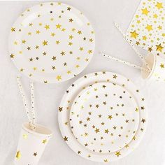 the table is set with gold stars on white plates and napkins, along with two cups and saucers