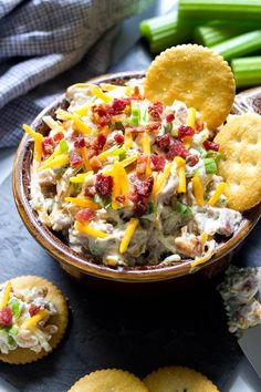 a bowl filled with chicken salad next to crackers and celery