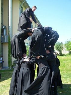 a group of people standing around each other in front of a house wearing black clothing