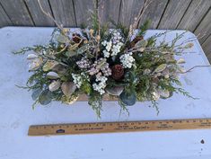 a bouquet of flowers sitting on top of a white table next to a ruler and wooden plank