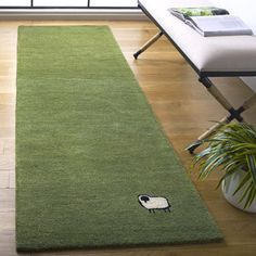 a green rug with a black and white sheep on it in front of a window