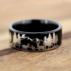 a black and white ring with trees and animals in the background on a wooden surface