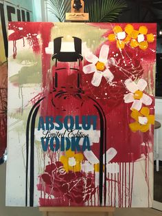 an art piece is displayed on a easel in front of a painting that says absolut vodka