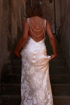 a woman in a white dress is walking up some stairs with her back to the camera