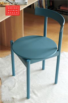 a blue chair sitting on top of a white rug next to a wooden desk and bookshelf