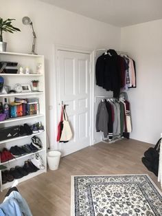 a room with white walls and shelves filled with clothes, shoes and other items on the floor